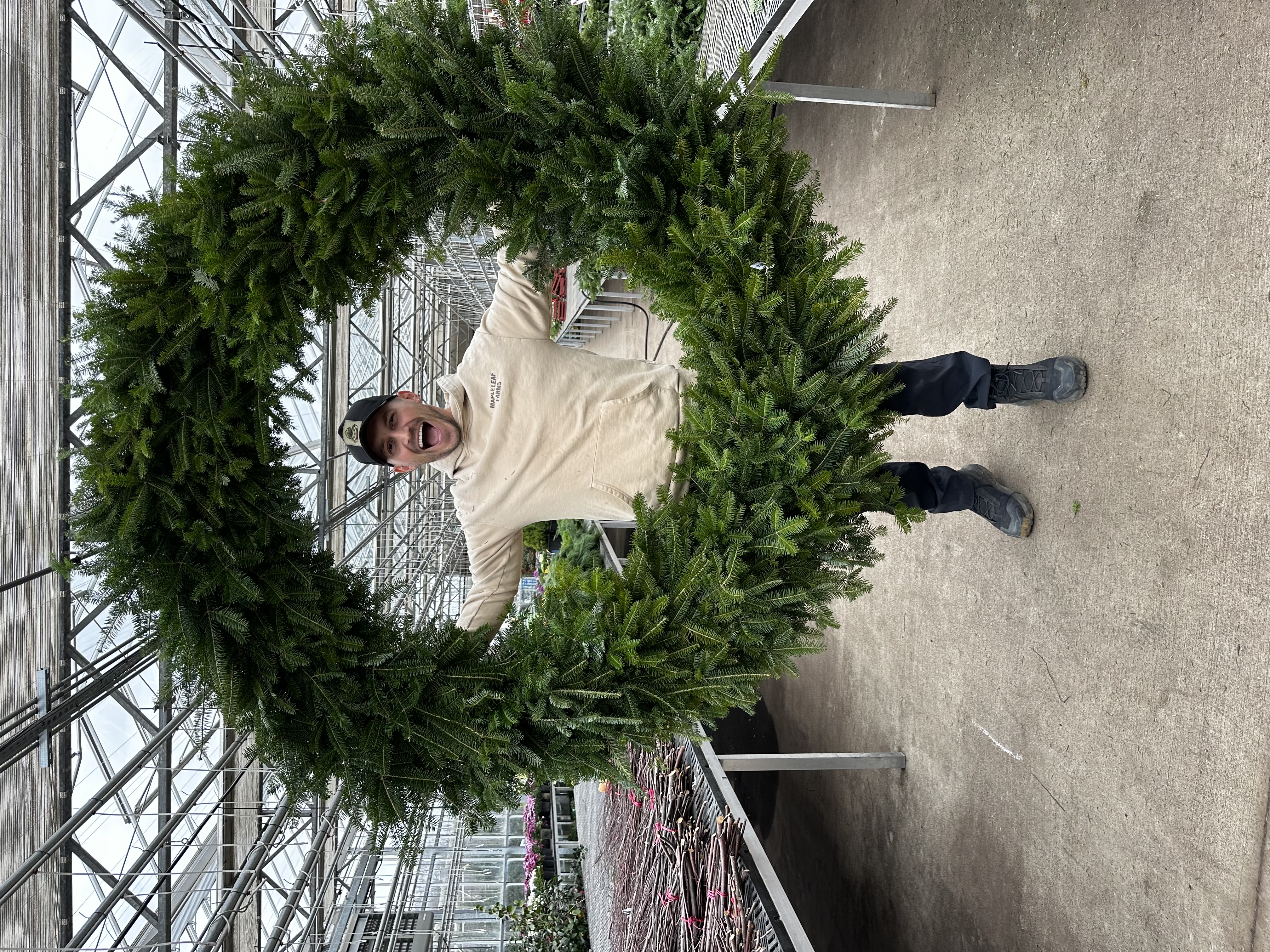 A Maple Leaf Farms team member holding a giant evergreen wreath